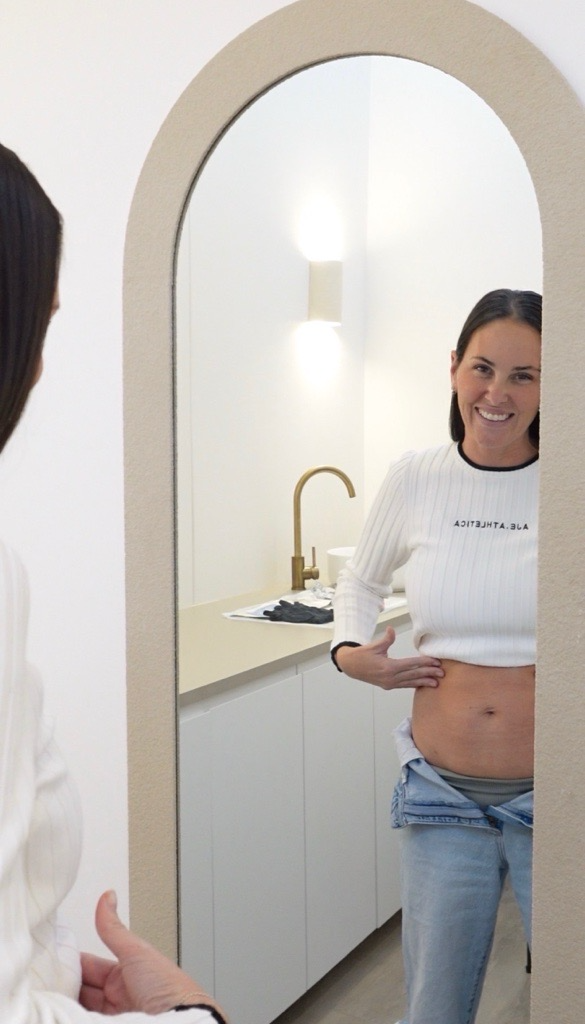 A client standing at the clinic mirror during a body consultation