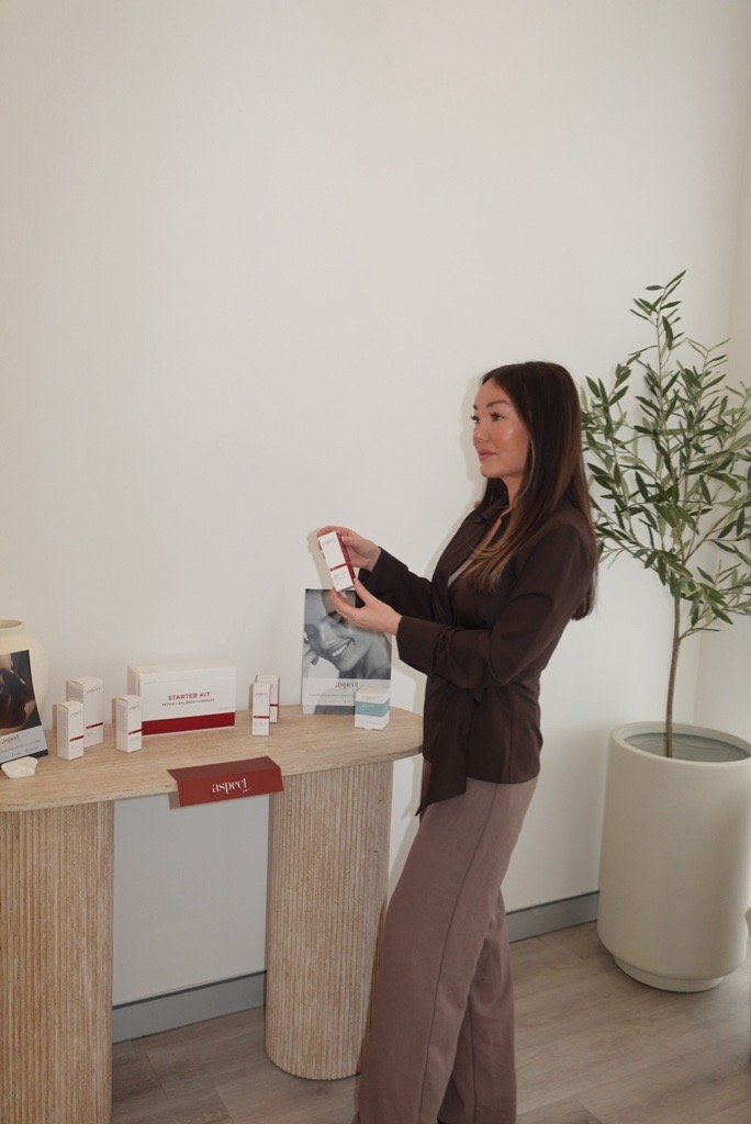 Breigh presenting Aspect Dr skincare beside the clinic’s product display